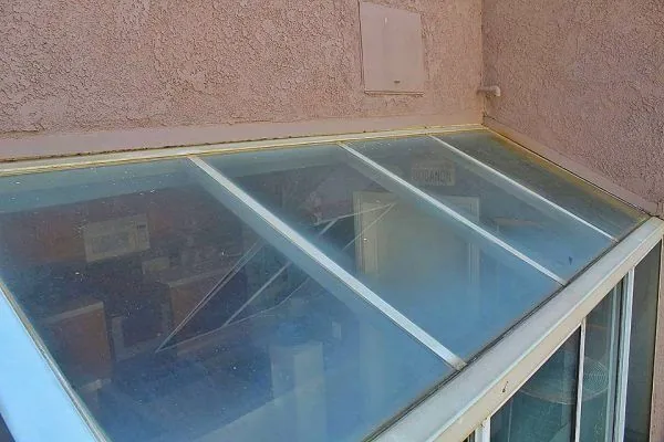 Sloped glass canopy with visible surface haze before cleaning