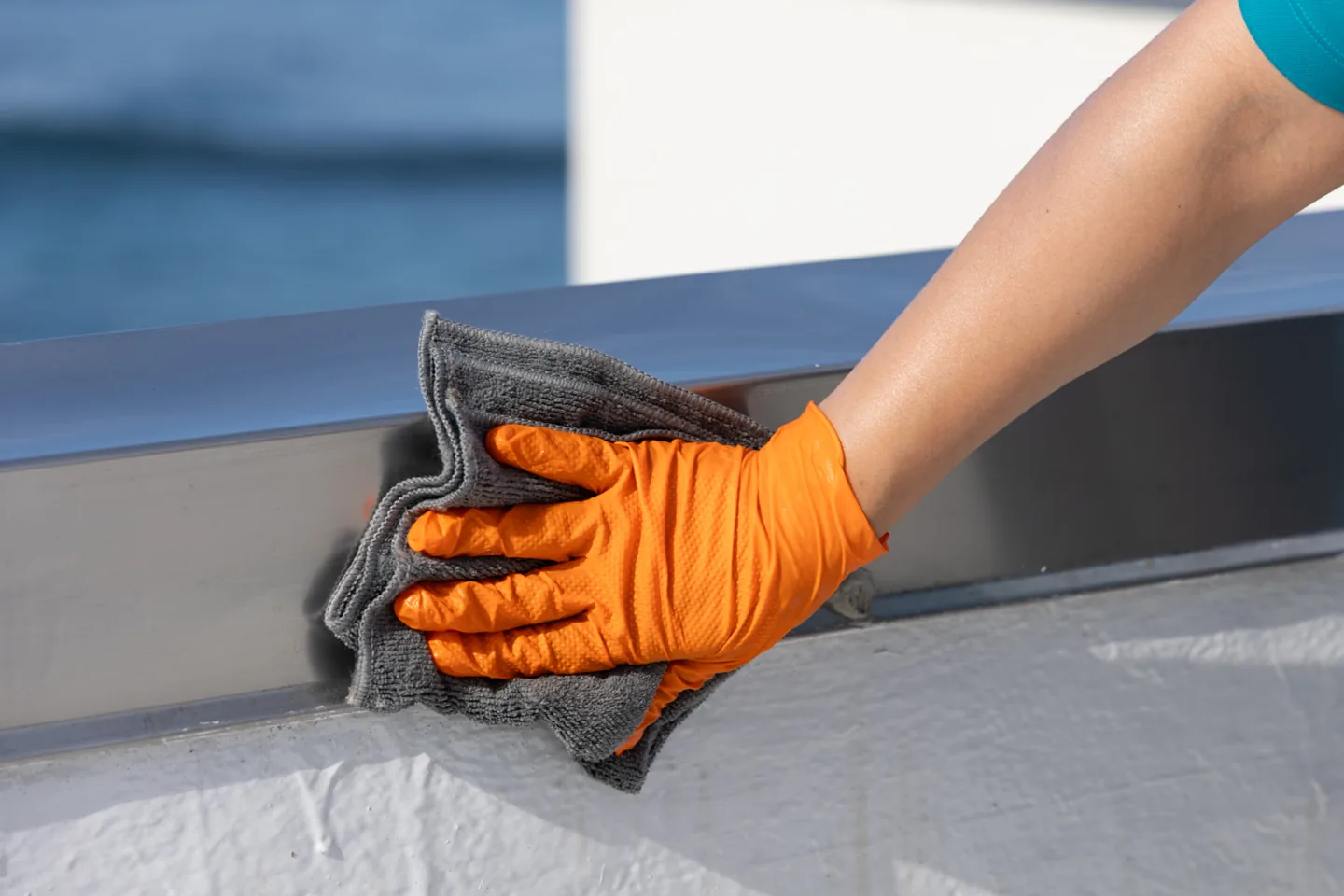 Gloved hand wiping a window frame with a microfiber cloth