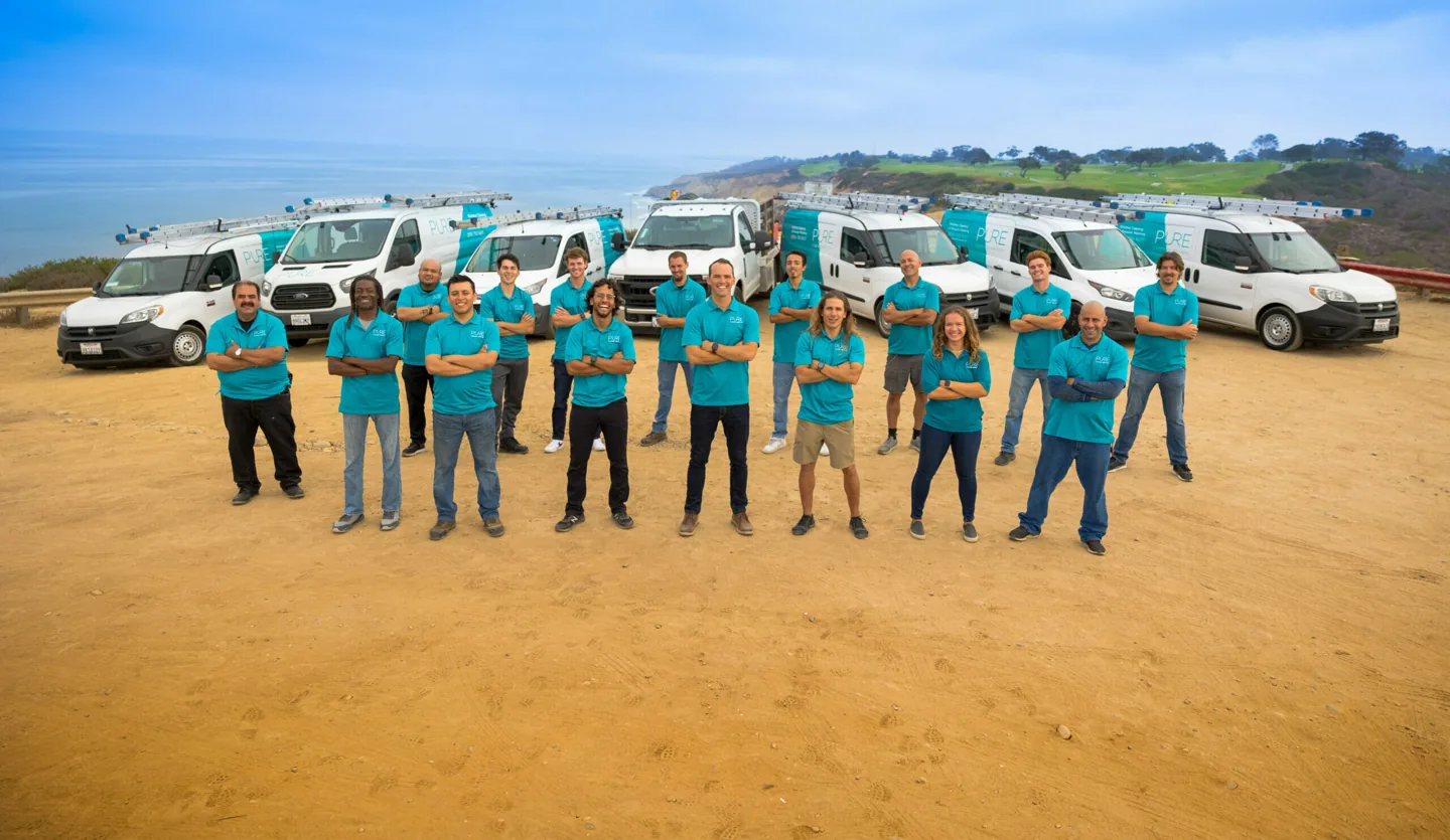 PCS crew in blue shirts standing with branded service vans beside the coast