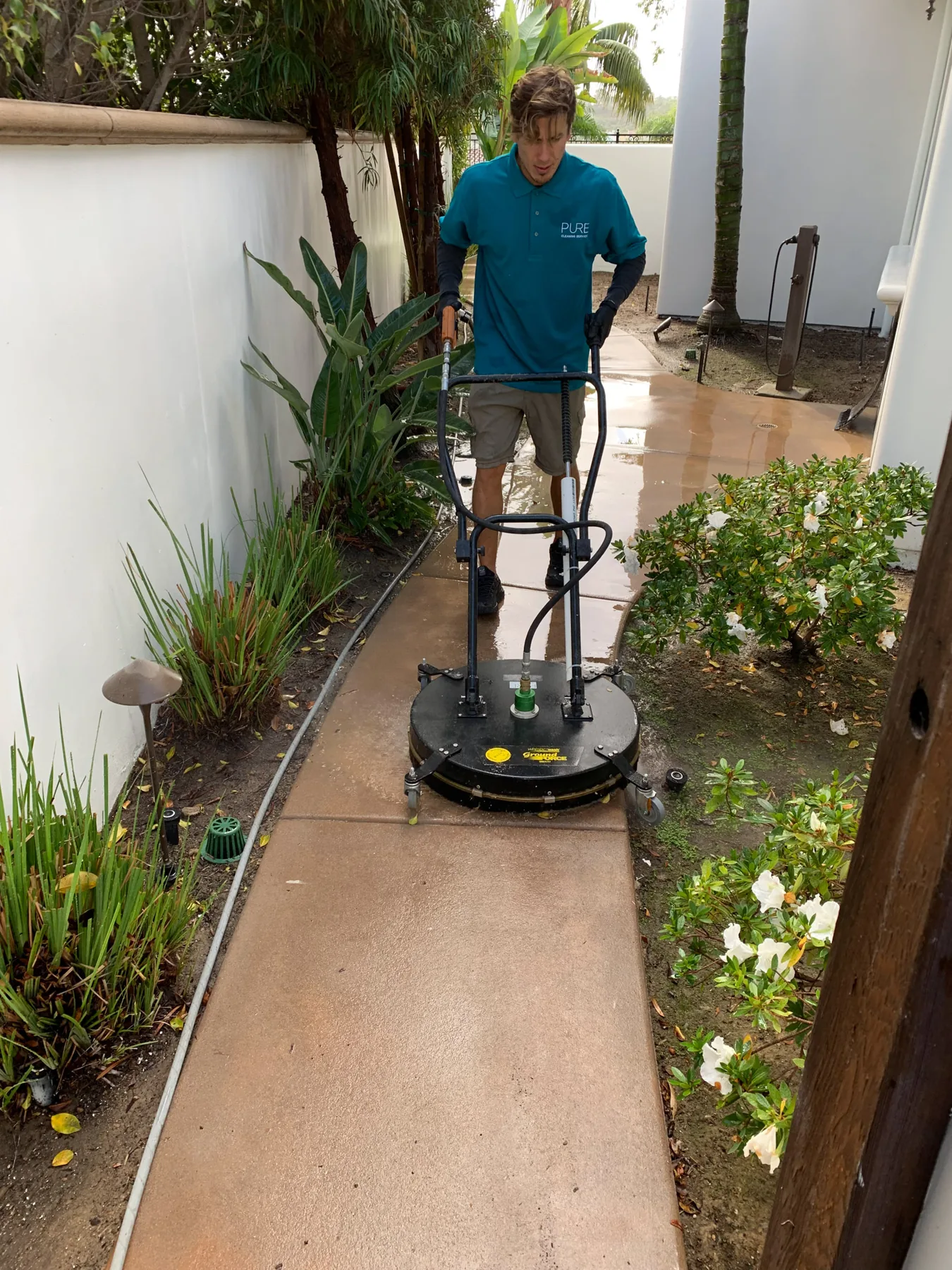 PCS technician using a surface cleaner along an outdoor walkway
