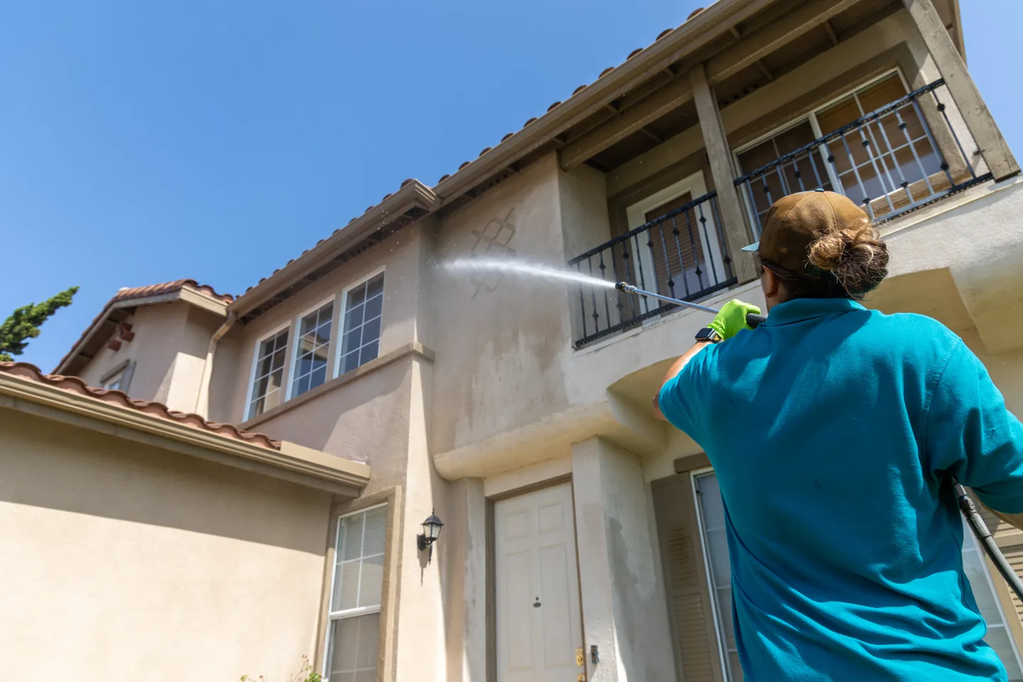 PCS technician washing the stucco exterior of a two-story home